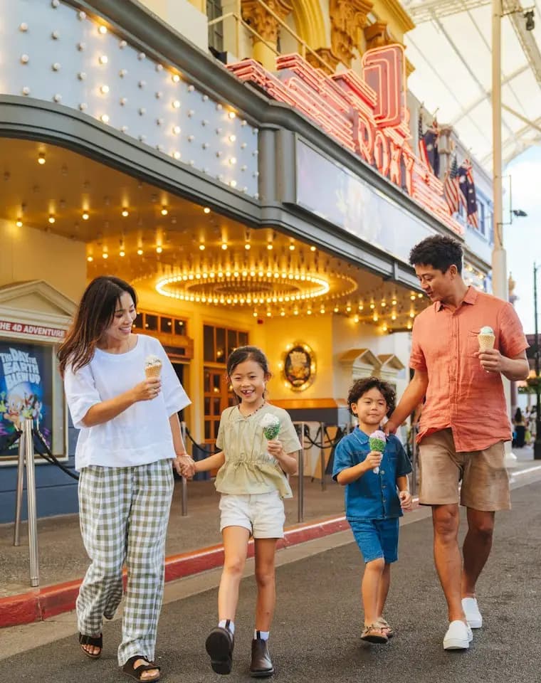 Family walking past a theater eating ice cream cones