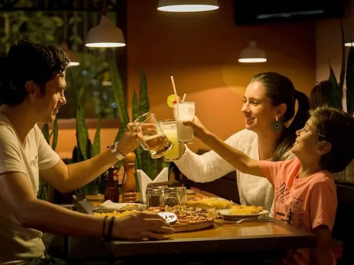 Family toasting over pizza at a restaurant